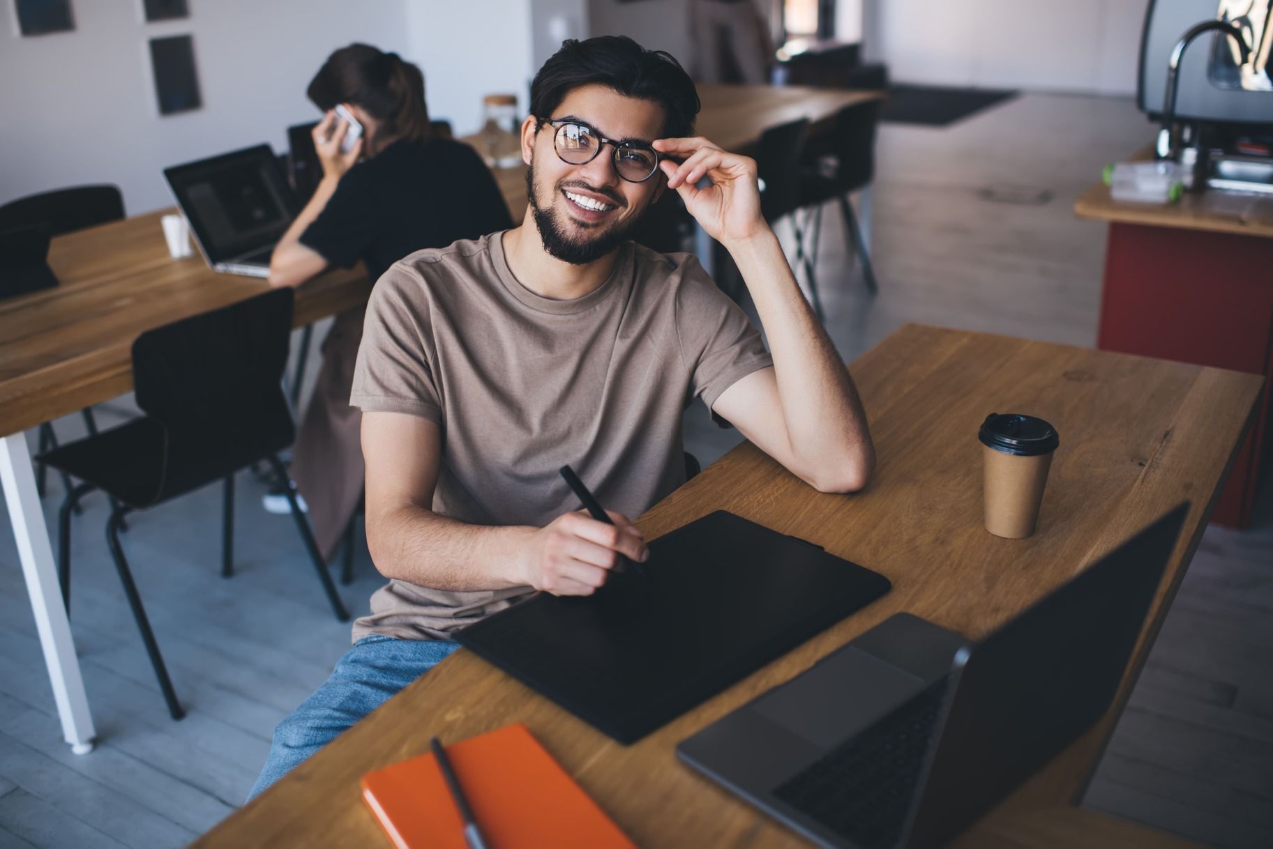 cheerful-young-man-sitting-at-table-with-laptop-2025-03-26-07-32-16-utc-1.jpg
